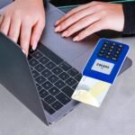 Person making an online payment using a laptop and card reader.