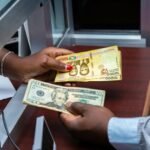 Burundian franc and US dollar exchange transaction at bank counter.