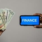 Image depicting currency and finance concept with hands holding cash and a smartphone.